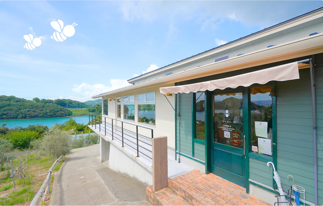はちみつcaféオリーブハニーの外観。青と白を用いた海に面するおしゃれなカフェ。